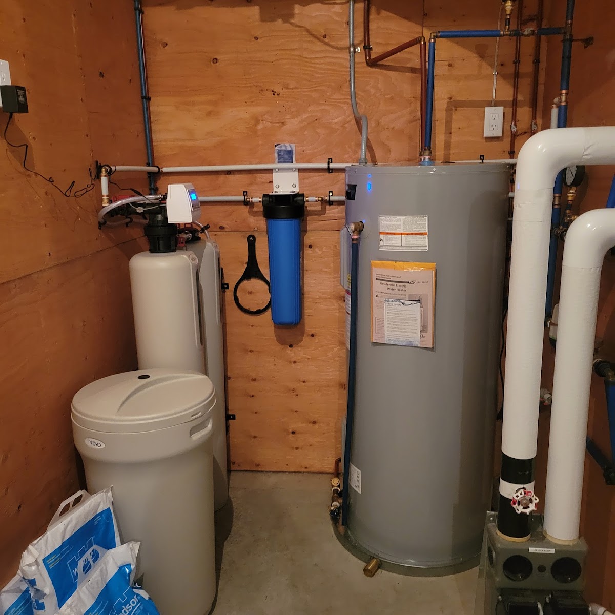 Neatly run copper and PEX piping feeding a water heater and whole-home filtration
